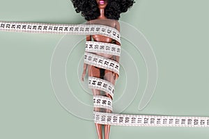 Doll wrapped in measuring tape. Tied up unrecognizable plastic doll, weight loss, fasting and slimming, diet, anorexia