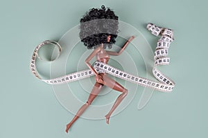 Doll wrapped in measuring tape. Tied up unrecognizable plastic doll, weight loss, fasting and slimming, diet, anorexia photo