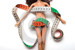 Doll wrapped in measuring tape on white background -  female fight for a perfect body - Dieting concept