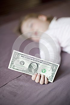 Dollar banknote in hand of baby sleeping