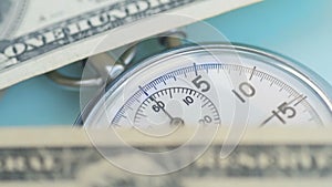 Dollar banknotes flying over the stopwatch dial. Financial money concept