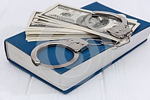 Dollar banknotes with handcuffs on blue book