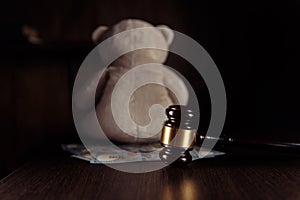 Dollar banknotes, judge gavel and teddy bear on a wooden table. Divorce, separation and alimony concept