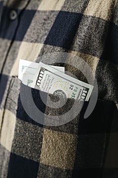 Dollar banknotes in pocket of shirt, cash payment and financial concept.