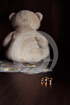 Dollar banknotes, rings and teddy bear close-up. Divorce, separation and alimony concept