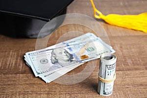 Dollar banknotes and student graduation hat on background. Tuition fees concept