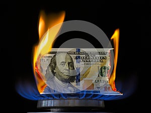 Dollar bill on fire in gas burner flame.