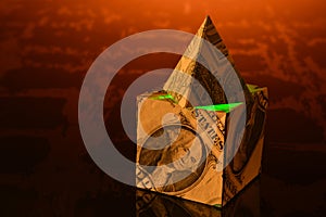 Dollar bill pyramid resting atop a cube made of dollar bills