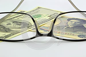 Dollar bill and yen with eyeglass