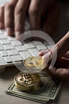 Dollar bills, bitcoins and man using a computer
