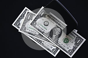 Dollar bills on a black background and a hole punch