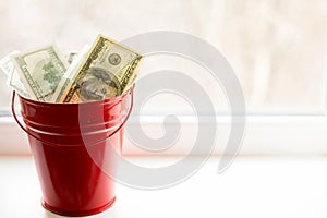 Dollar bills in red pail. on white window.light background. top view. a lot of money