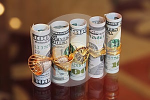 Dollar bills rolls money with gold jewelry rings