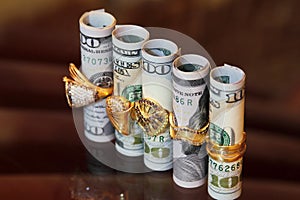 Dollar bills rolls money with gold jewelry rings