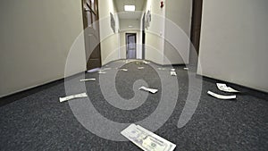 Dollar bills are scattered on the floor of the hotel or office. Camera movement on the bill