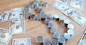 Dollar bills and stacks of coins in shape of dollar sign on table