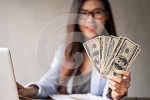 Dollar in a businesswoman hand. A Asia woman is working from home or office and glad to get dollar money from work and from a