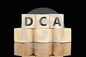 Dollar cost averaging DCA text on wooden cubes on a black background