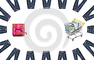 Dollar and euro bills mixed up in shopping cart and red gift box encircled with multitude of jeans on white background. Isolated.