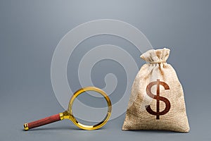Dollar money bag and magnifying glass. Financial audit. Origin of capital and legality of funds. Search and attraction photo