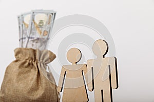 Dollar money bag with wooden figures of people on white background. Family savings concept. Close-up