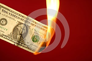 Dollar note burning in fire over red