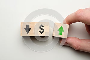 Dollar rising growth concept - hand holds cube with green arrow next to dollar sign