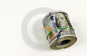 Dollar roll tightened with band. Rolled money isolated on white.