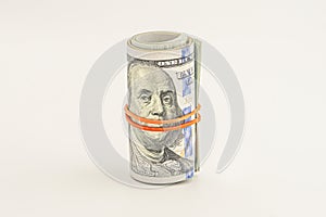 Dollar roll wrapped with red ribbon. 100 dollar bills on a roll isolated on white background. Rolled up money isolated