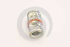 Dollar roll wrapped with red ribbon. 100 dollar bills on a roll isolated on white background. Rolled up money isolated