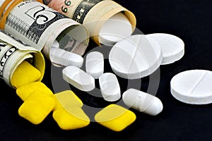 Dollar rolled up with pills flowing out isolated on black background, high costs of expensive medication concept. Copy space -