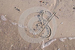 Dollar sign painted on the sand of beach is washed off by a sea