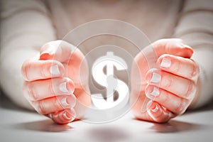 Dollar sign between woman's hands in gesture of protection. Currency stability