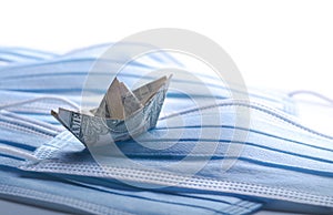 Dollar tosses on the waves. Financial problems metahor, banknote origami-ship with surgical masks.