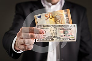 Dollar vs euro. Business man in suit holding 50 euros.