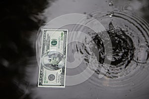 Dollar on water surface, black background