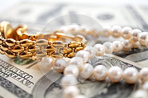 Dollars background with gold watch and pearls conceptual image