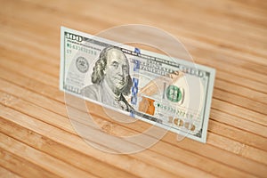 100 Dollars bill and portrait Benjamin Franklin on USA money banknote. Hundred dollar bills on wooden background