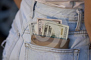 Dollars bills in a leather wallet in a jeans rear pocket