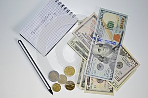 Dollars, euro cents, notebook and pen on a white background