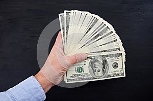 Dollars in a hand on a black background.
