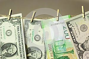 Dollars are hanging on the clothesline clothespins attached on a gold background