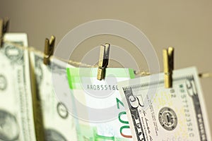 Dollars are hanging on the clothesline clothespins attached on a gold background