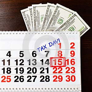 Dollars money, April 15 on calendar and Tax Day phrase, wooden b