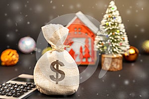 Dollars money bag on the background of a Christmas tree, house and snow.