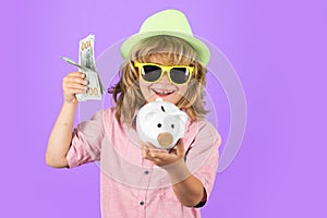 Dollars money banknotes and piggy bank concept. Portrait of a little boy putting money on a moneybox. Child saving money