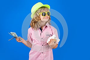 Dollars money and piggybank concept. Portrait of a little boy putting money on a moneybox. Child saving money in a