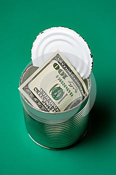 Dollars in an open tin can. Safeguarding cash, stash concept. Time to get the deferred, accumulated money. Green background