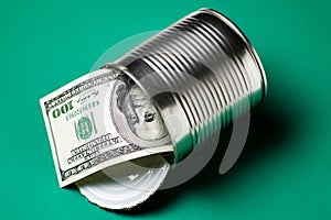 Dollars in an open tin can. Safeguarding cash, stash concept. Time to get the deferred, accumulated money. Green background