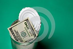 Dollars in an open tin can. Safeguarding cash, stash concept. Time to get the deferred, accumulated money. Green background